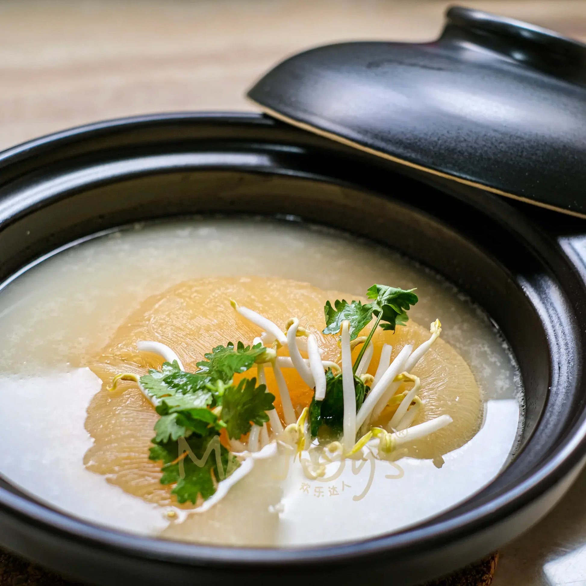 claypot dish with sharkfin and bean sprout in a black claypot on a wooden table