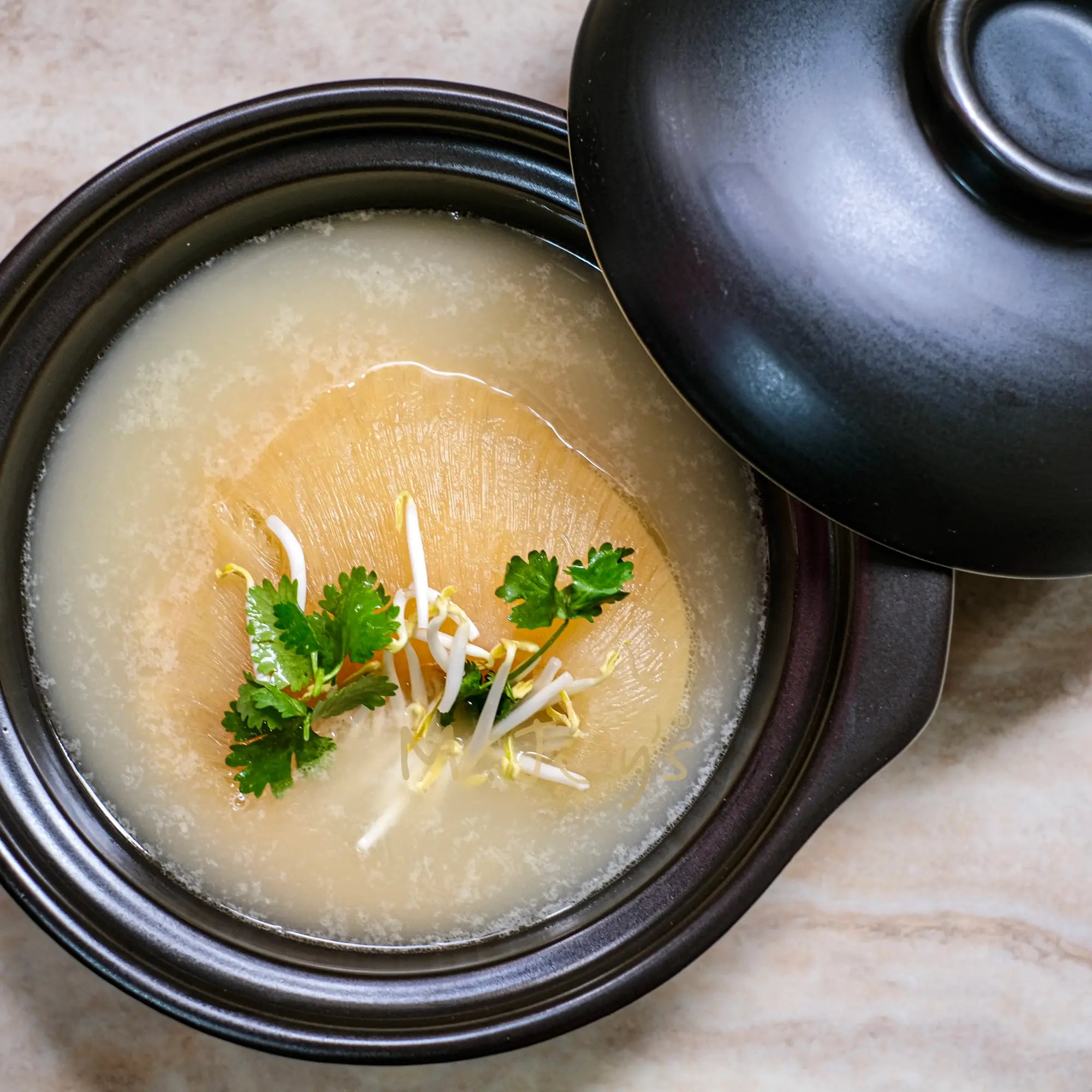 Hot pot with a black lid on a beige surface